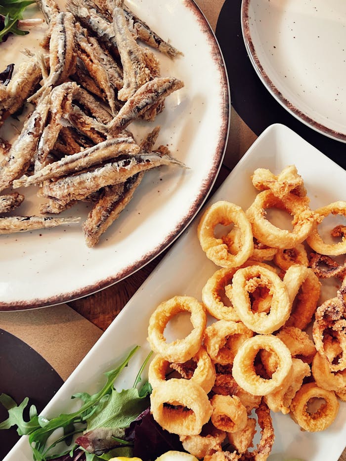 Tasty seafood platter featuring crispy fried calamari and small fish, garnished with fresh greens.