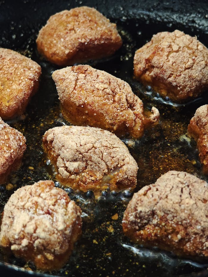 Close-up of crispy fried chicken pieces cooking in hot oil.