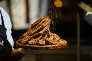 Appetizing grilled lamb chops seasoned with herbs and spices served on a wooden platter.