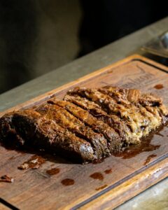 Delicious sliced grilled steak on a wooden cutting board, perfect for BBQ or steak lovers.