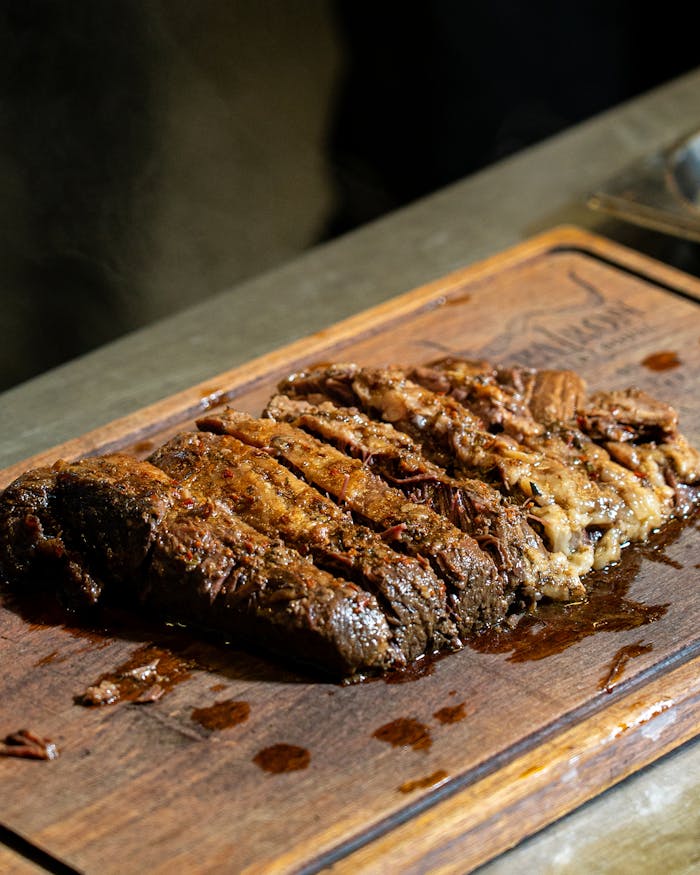 Delicious sliced grilled steak on a wooden cutting board, perfect for BBQ or steak lovers.